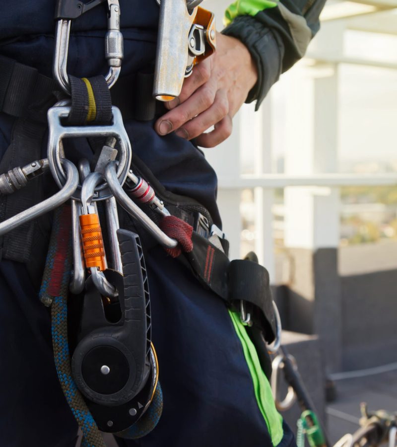 Equipment of industrial mountaineering worker on roof of building during industrial high-rise work. Climbing equipments before starting job. Rope laborer access. Concept of urban works. Copy space