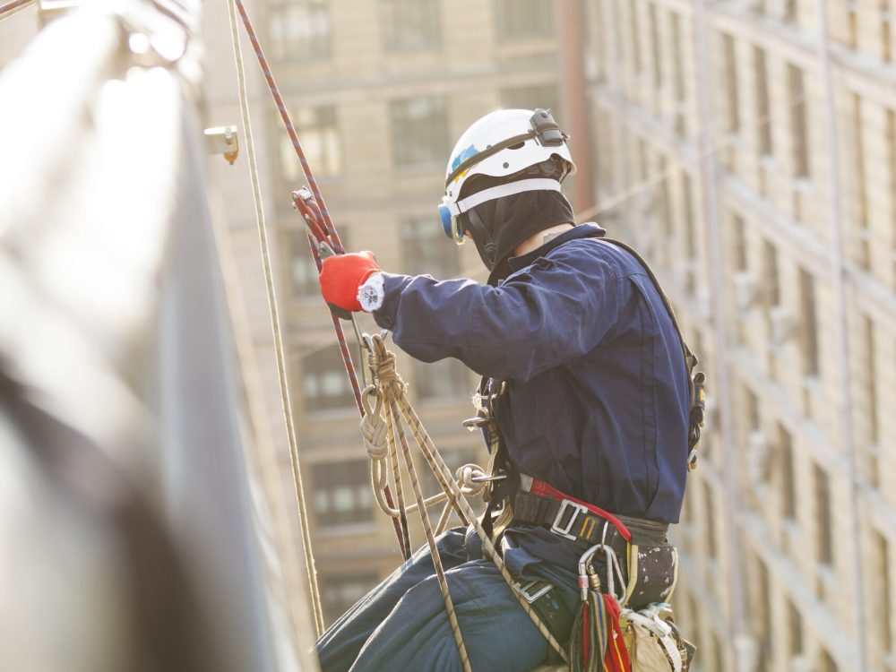 Industrial climber lowering from a roof of a building